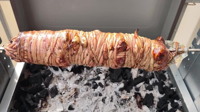 View of a traditional Greek kokoretsi, roasting on a spit over charcoal for Easter celebrations. Kokoretsi or kokorec is a dish of the Balkans and Anatolia (Asia Minor).