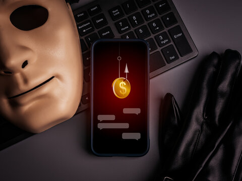 Phishing scam concept with hacker mask, gloves, and smartphone showing fake chat messages with coin on hook. Online fraud, scammer attack, money theft, and cyber crime targeting digital users.