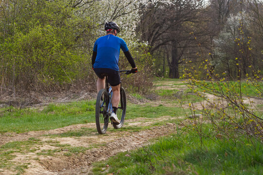 Mountain Biker Riding Off-Road Trail Through Spring Forest Landscape | Rowerzysta MTB jadący szlakiem terenowym na tle wiosennego leśnego krajobrazu