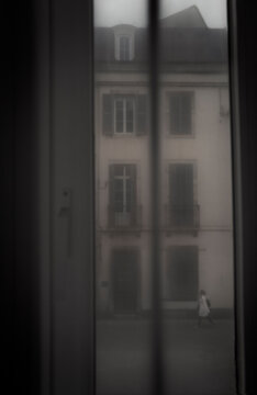 Blurred, suggestive and romantic scenery street  through net curtains of one lady walking in an european street