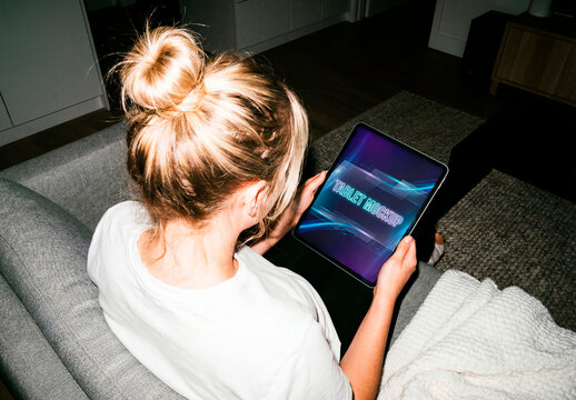 Woman using tablet mockup while sitting on sofa at home