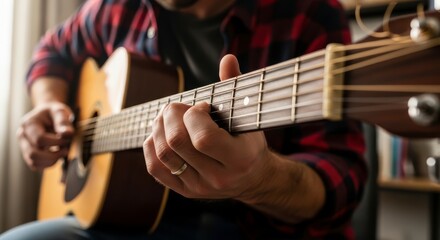 Obraz premium Man playing acoustic guitar, close-up on hands and fretboard, casual indoor setting, warm lighting