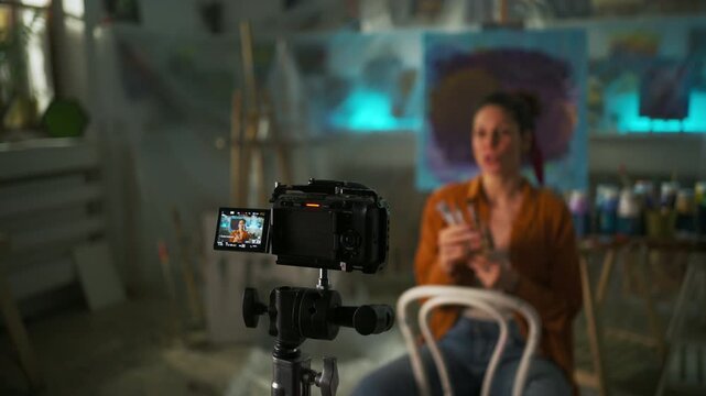 Female Educator Displays Painting Brush Skills Animatedly Before Camera In Studio Environment