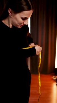 Woman measures body parts in front of mirror using a tape measure in her home