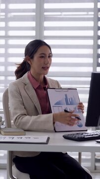 Asian adult businesswoman presenting financial data charts graphs explaining business strategy analysis corporate meeting office