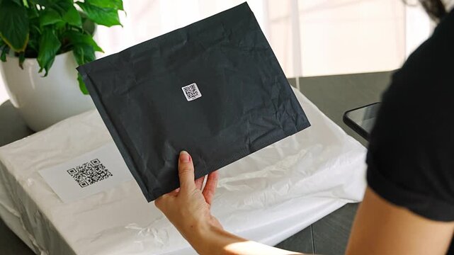 Person scanning QR code on parcel with smartphone camera with focus on mobile device screen. Digital app interface and contactless delivery service concept.