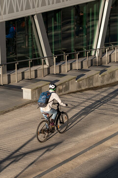 Urban cyclist on bicycle near modern architecture in Stockholm Sweden as sunlight and shadow cross the street in motion during daily commute