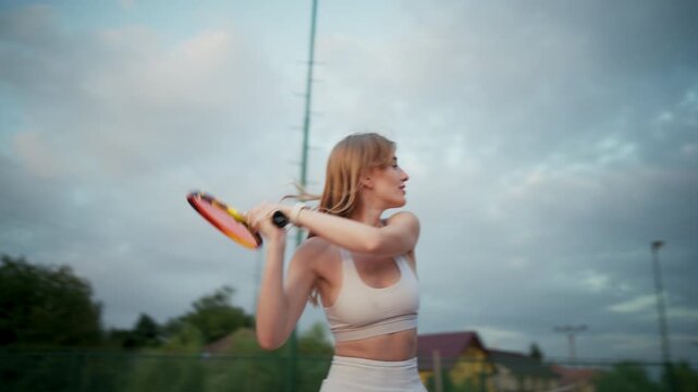 Evening Tennis Routine. Female Athlete On Clay Court Practicing Dynamic Backhand Skillfully