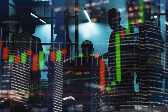 Business people discuss financial charts at night inside an office building with city lights in the background