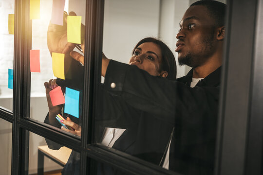 Team members work together on sticky notes in an office setting during afternoon hours to brainstorm ideas and organize tasks
