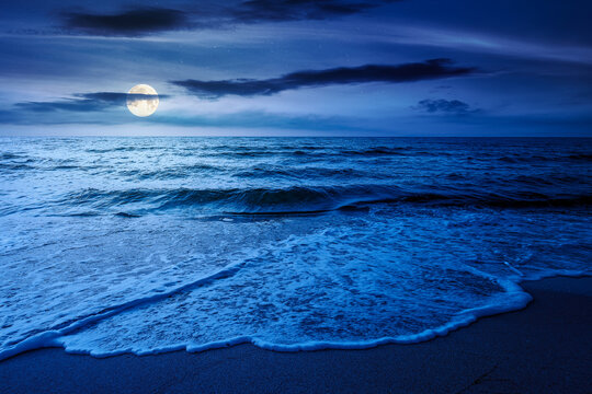 autumn vacation at the sea at night. full moon over beautiful seascape. calm waves wash the sandy beach. image with cloudy sky above horizon. mysterious background for fantasy or ads placement