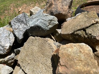 Obraz premium A detailed close up of a pile of large, rough natural granite rocks and stones with visible textures under bright daylight.