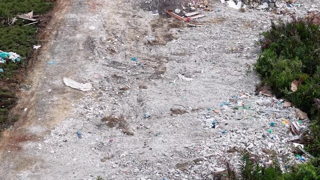 Aerial footage showing an outdoor rubbish dump with scattered construction debris and vegetation.