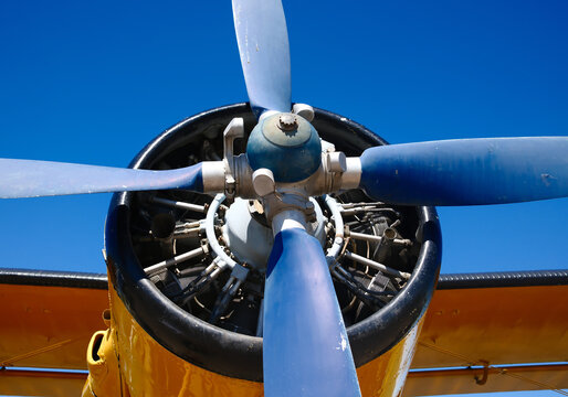 Closeup of aircraft radial engine with three blade propeller against blue sky at outdoor aviation airshow