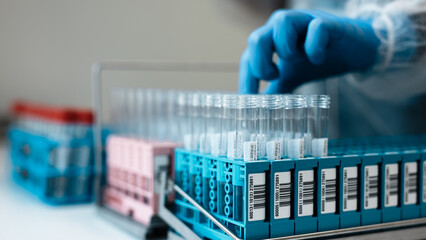 Laboratory technician in blue gloves organizes blood test tubes in a rack, showcasing various labeled vials and a clean, sterile laboratory environment © wedmoments.stock