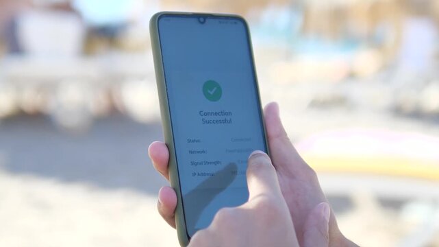 Smartphone showing successful Wi-Fi connection on a sunny beach. Close-up of a hand holding a phone with Connection Successful message outdoors. Ideal for digital nomad, remote work, and travel tech