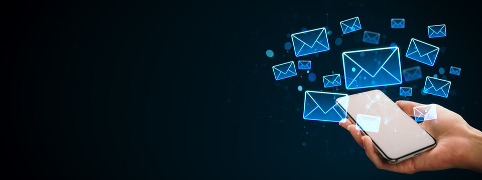 Digital email envelope icons floating above a smartphone in hands on dark background showing modern online communication and messaging concept.
