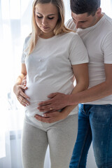 Fototapeta premium Pregnant woman with a man at home. Selective focus.