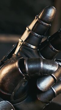 Vertical video: Sliding camera showing metal gauntlet opening fingers on dim bench, showing rivets