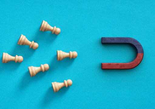 Magnet attracting chess pawns for business strategy and marketing