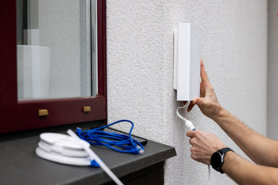 service provider worker installing 5G internet antenna on house outdoor wall