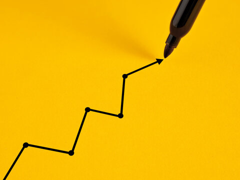 Marker drawing growing line graph on yellow background