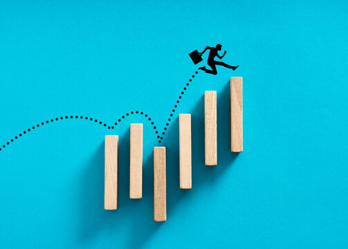 Businessman silhouette jumping over wooden blocks showing growth