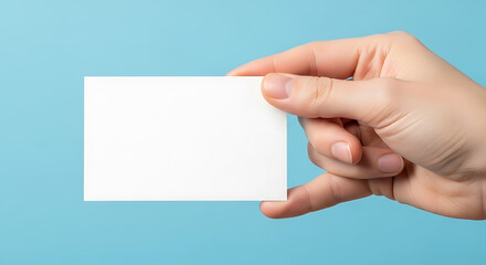 Obraz premium Hand holding blank white card against blue background image