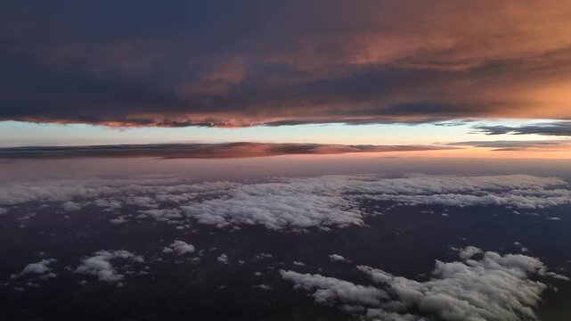 An immersive cockpit view flying between layers of stratus clouds bathed in sunrise light, with a blue horizon at the back. 4K ultra-realsitic shot