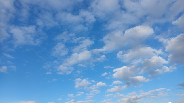 White fluffy clouds scattered across a bright blue daytime sky