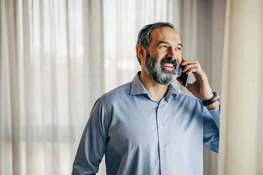 Smiling businessman talking on phone near window