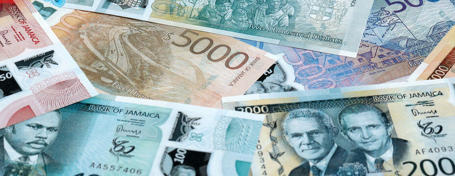 Jamaican dollar money banknotes pile on table. Jamaica bills of JMD currency close up