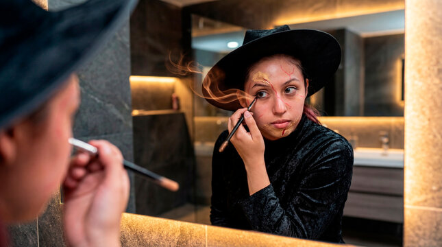Spellbound woman applying witch makeup in modern bathroom mirror