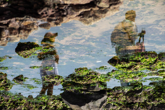 Reflection of devotees in a tidal pool