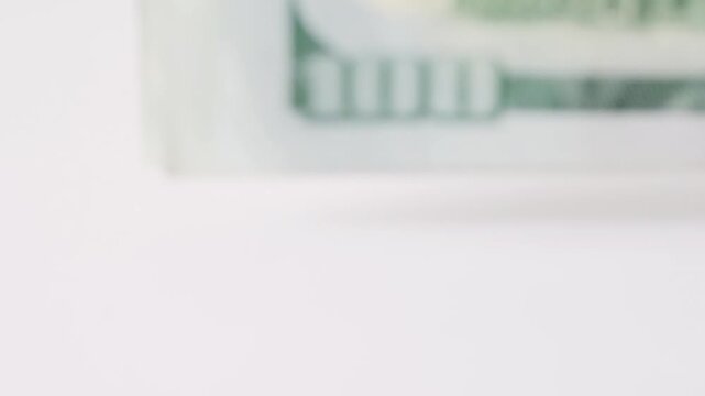 Soft focus edge hundred dollar bills blurring, outoffocus stack on white plane with pastel green hue, investor hesitation and trader uncertainty implied, subtle bokeh and muted