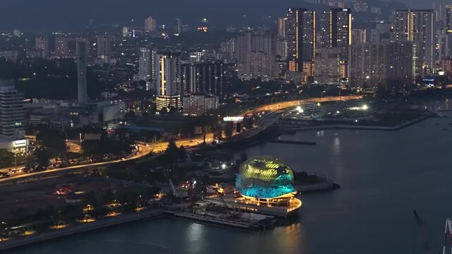 Aerial night view of Lin Xiang Xiong Art Gallery illuminated on waterfront with surrounding city skyline.