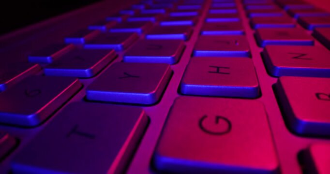 sliding above laptop computer keyboard in neon lights. cyberspace, gaming concept