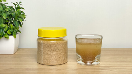 A jar of psyllium husk and a glass of dissolved fiber on a wooden surface. A visual demonstration of how to prepare a healthy drink to support digestion. © Lisi4ka