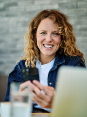 Portrait of a smiling young woman girl using a mobile phone and laptop computer with a coffee cup...
