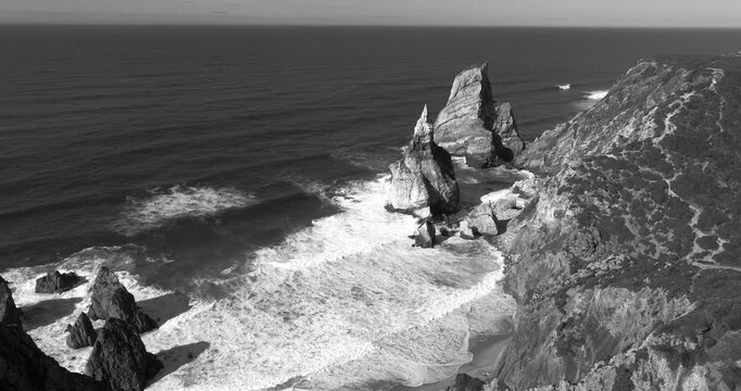 Praia da Ursa Sintra Portugal Atlantic seascape and dramatic cliffs aerial. Black and white monochrome cinematic establishing shot