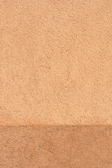 Fototapeta premium Horizontal division between light and dark pastel apricot stucco wall texture with a rough sandy finish suitable for architectural backgrounds.