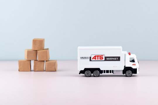 White toy truck with ATB emblem with boxes on light background, space for text.