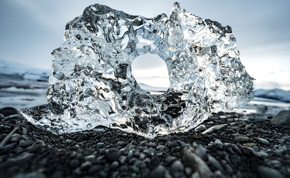 Ice, ice chunks with hole at the black gravel beach, glacier lagoon J&ouml;kuls&aacute;rl&oacute;n, glacier lake, southern edge of Vatnaj&ouml;kull, southeast Iceland, Iceland