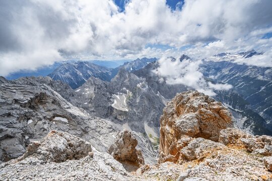 At the summit of the Partenkirchner Dreitorspitze, view into the Reintal valley towards cloud-covered peaks, mountain panorama with ridge of the Oberreintalschrofen and Gro&szlig;er Hundstallkopf, Zugspitzplatt in the background, Wetterstein range, Garmisch Partenkirchen, Bavaria, Germany