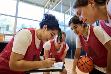 Obraz premium Female basketball players discussing game strategy with coach