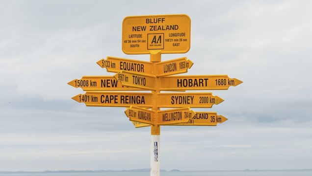 Yellow signs, signpost with different destinations, cities and distances, Bluff, South Island, New Zealand