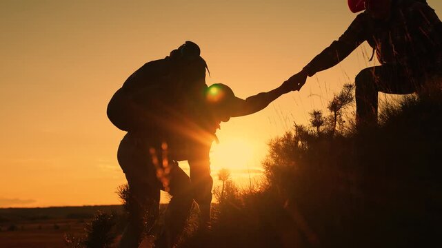 Travelers man woman helping hand climb mountain, hill, silhouette. Teamwork business people ascending to pinnacle of success. Team businessmen working toward their goal. Tourists, nature, People hiker