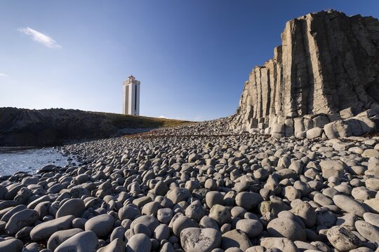 Basalt cliff, beach with rounded stones and lighthouse, K&aacute;lfshamarsv&iacute;k, Skagi Peninsula, Iceland