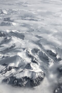 View from the plane to snow-covered mountainous landscape, bird's eye view, Greenland