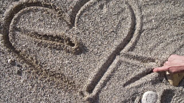 Heart sand beach where a person draws an arrow through a heart shape to symbolize romance and love